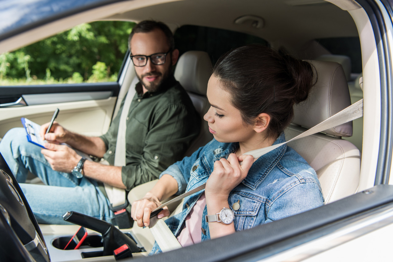 Un moniteur souriant expliquant un point à un élève en voiture, symbolisant la formation de qualité.